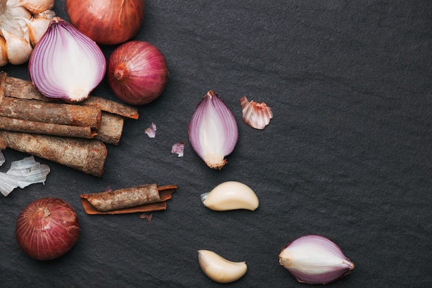 Ingredientes de cozinha: paus de canela e alho na mesa de pedra preta.