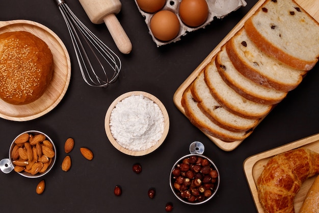 Ingredientes de pães caseiros, farinha, amêndoas nozes, ovos em fundo escuro