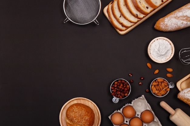 Ingredientes de pães caseiros, farinha, nozes amêndoas, avelãs, ovos em fundo escuro.