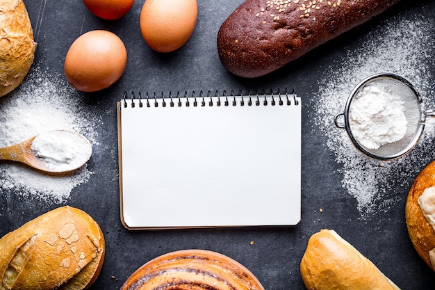 Ingredientes de panificação para produtos de panificação farinha e centeio. Pão torrado fresco, baguete, pães em um fundo preto lousa.