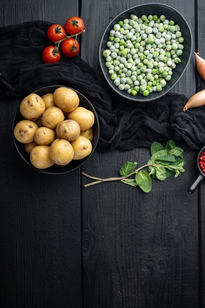 Ingredientes de purê de batata com ervilha e hortelã, camada plana, sobre fundo preto de madeira com espaço para texto