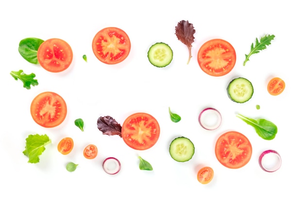 Ingredientes de salada de vegetais frescos filmados de cima em um fundo branco Uma composição plana com fatias de tomate, pepino, cebola e folhas mezclun formando uma moldura com espaço de cópia