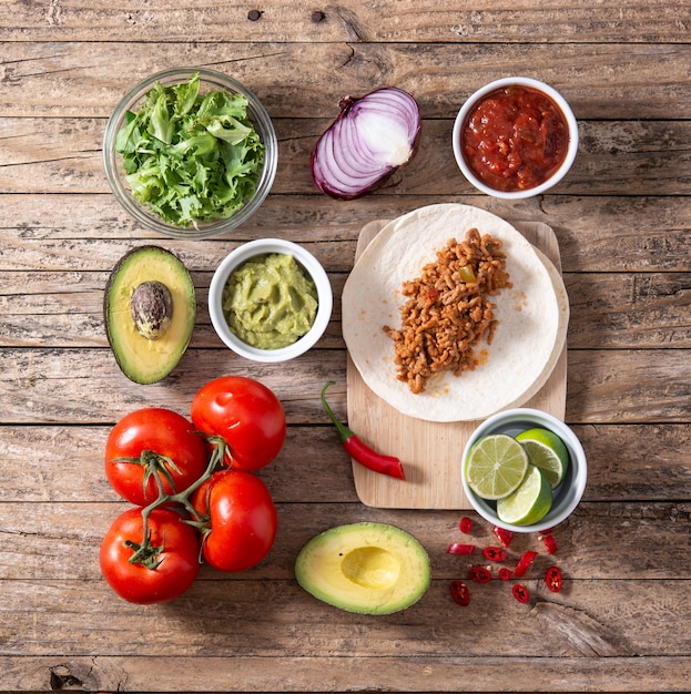 Ingredientes de tacos mexicanos na mesa de madeira.