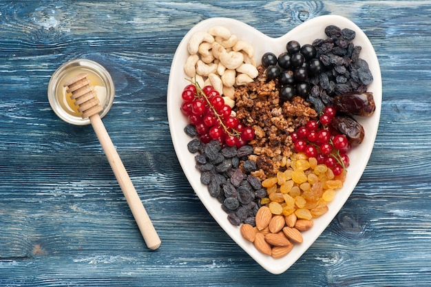 Ingredientes para un desayuno saludable bayas nueces granola frutos secos miel sobre fondo de madera vista superior horizontal