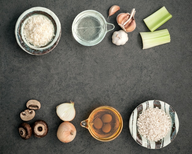 Ingredientes do risoto dos cogumelos no fundo de pedra rústico escuro com espaço liso da configuração e da cópia.