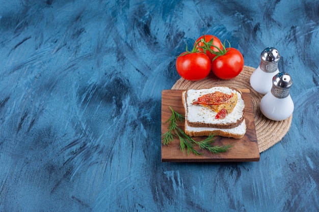 Ingredientes do sanduíche fresco em uma placa, na mesa azul.