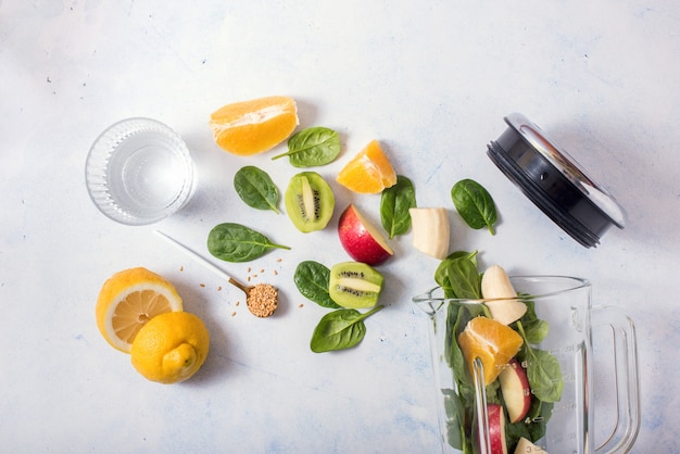 Foto ingredientes do smoothie no misturador, preparação de smoothie com espinafre, maçã, laranja, kiwi, alimentação saudável, desintoxicação e conceito de consulta nutricional