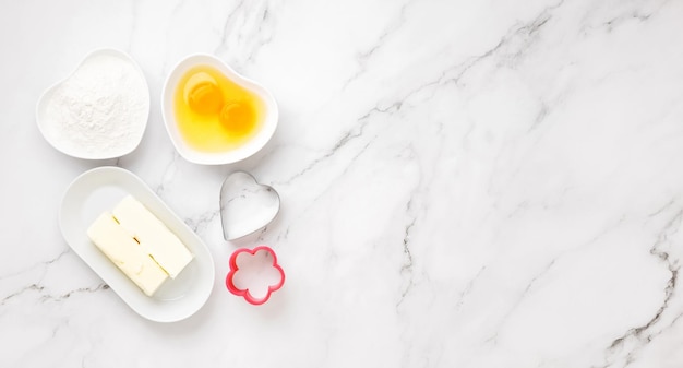 Ingredientes e formas para assar biscoitos na mesa de mármore. conceito de cozinhar com amor, cozinhar para seus entes queridos, assar para o dia dos namorados. vista do topo. copiar espaço