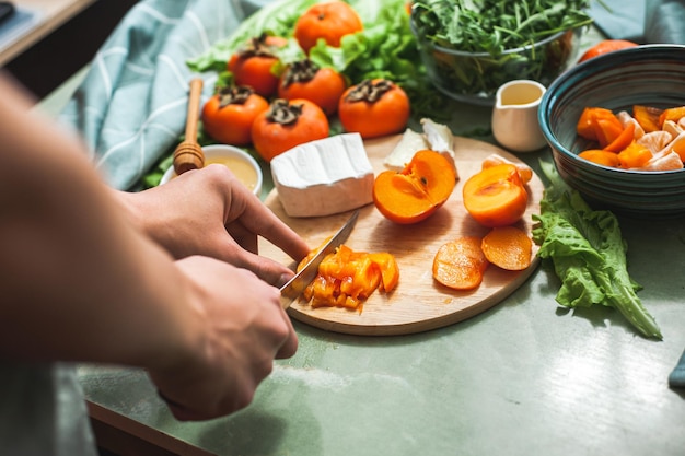 Ingredientes e processo de preparação de uma salada de vitaminas de inverno com caqui, tangerinas e queijo