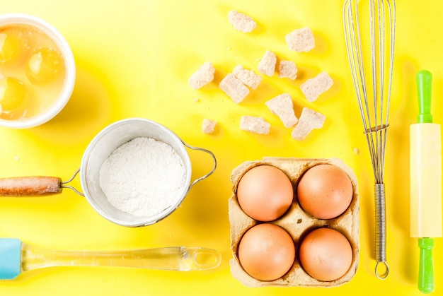 Ingredientes e utensílios para cozinhar o ovo, farinha, açúcar, bata, rolo, sobre fundo amarelo brilhante, vista superior