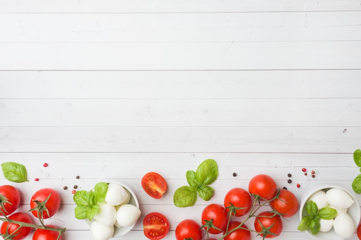 Los ingredientes para una ensalada caprese. Albahaca, bolitas de mozzarella y tomates.