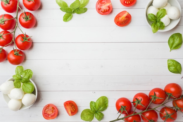 Los ingredientes para una ensalada caprese. Albahaca, bolitas de mozzarella y tomates.