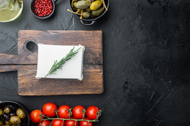 Ingredientes de la ensalada griega de queso feta, sobre fondo negro, plano con espacio para copiar texto