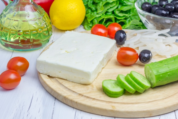 Ingredientes para ensalada griega en la tabla de cortar y mesa de madera