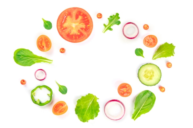Ingredientes de ensalada de verduras frescas disparados desde arriba sobre un fondo blanco Una composición plana con rebanadas de tomate, pimienta, pepino, cebolla y hojas mezcladas que forman un marco con un lugar para el texto