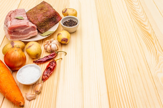 Ingredientes para estofado de carne con patatas y verduras. Filete de cerdo crudo, pechuga, especias en una superficie de madera, espacio de copia.