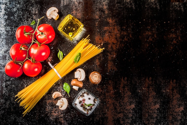 Foto ingredientes de fondo de alimentos para cocinar la cena. pasta espagueti verduras salsas y especias fondo oscuro oxidado