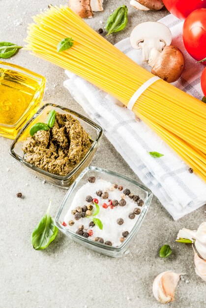 Ingredientes de fondo de alimentos para cocinar la cena. Pasta espagueti verduras salsas y especias fondo de piedra gris