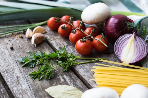 Ingredientes frescos para cocinar pasta, tomate y especias sobre mesa de madera con espacio de copia