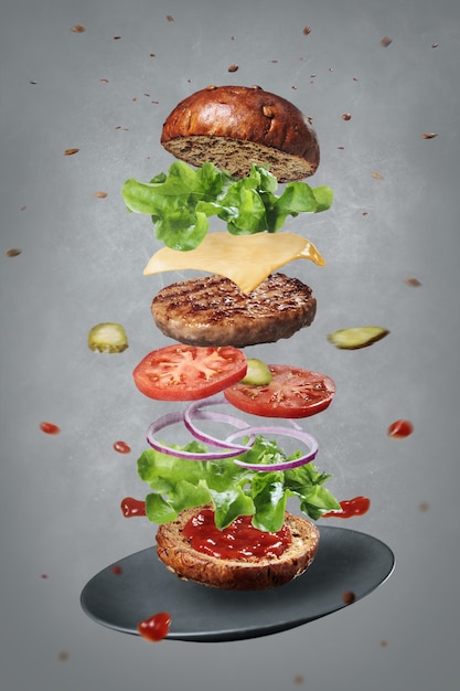 Ingredientes frescos de um delicioso hambúrguer quente levitando com um prato