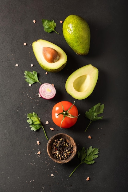 Ingredientes frescos para guacamole aguacate tomate cebolla cilantro sobre fondo negro