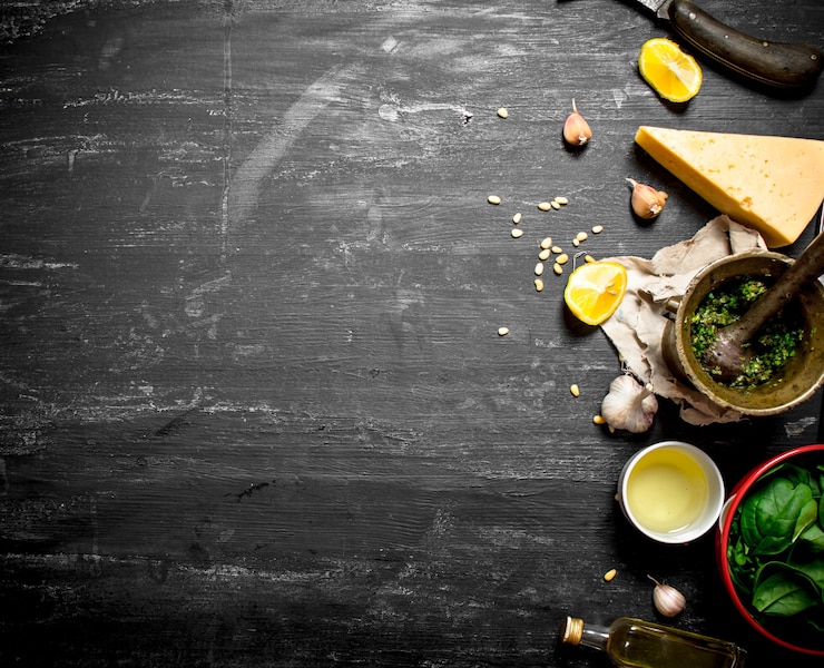 Foto ingredientes frescos para pesto italiano na mesa de madeira preta.