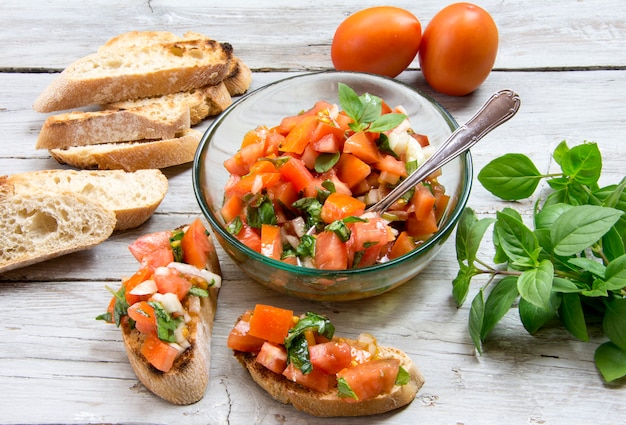 Ingredientes para hacer bruschetta, aperitivo típico italiano con tomate, albahaca y tostadas.