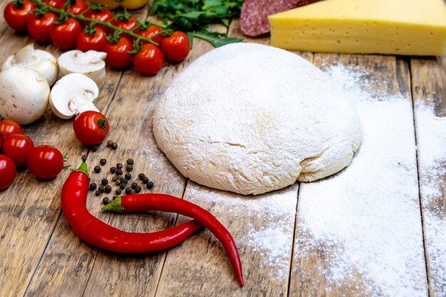 Ingredientes para hacer pizza, antes de hornear, en una mesa de madera, vista superior, receta paso a paso