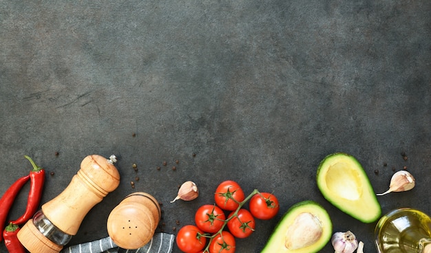 Ingredientes para hacer salsa de guacamole. Comida en una mesa negra de hormigón con espacio para texto.