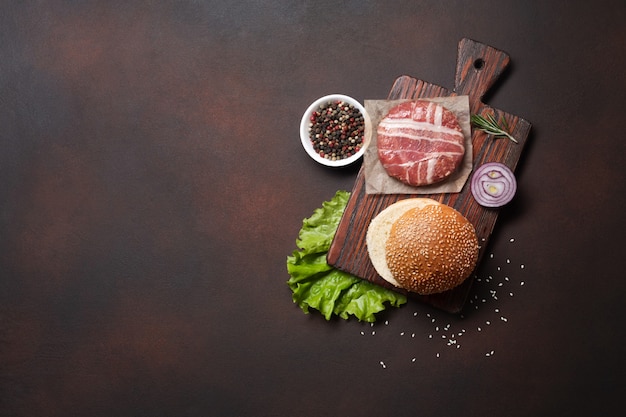 Ingredientes de hamburguesa chuleta cruda, lechuga, pan, queso, pepinos y cebolla