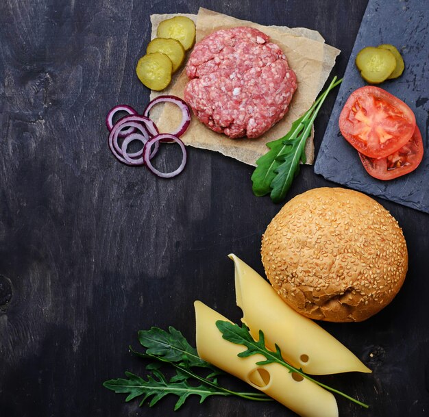 Foto ingredientes para hamburguesa: chuleta cruda, tomate, queso, cebolla.