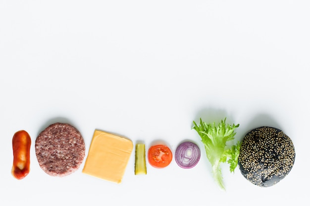 Foto ingredientes para la hamburguesa negra sobre fondo blanco.