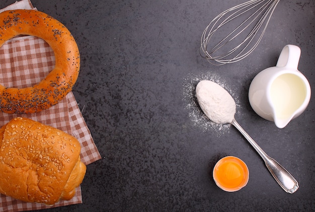 Ingredientes para hornear, harina, huevo, leche y batidor. bagel, croissant.