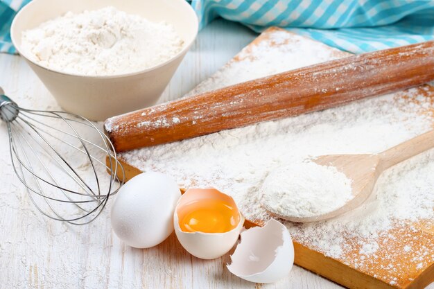 Ingredientes para hornear sobre fondo blanco de madera.