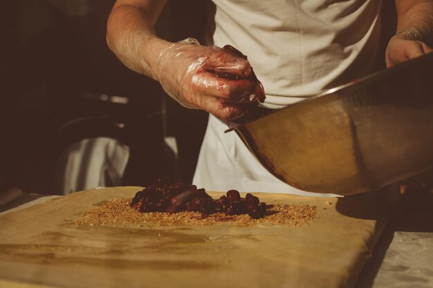 Foto ingredientes para hornear strudel relleno de cerezas enlatadas. el cocinero está preparando un strudel de cerezas. estilo rústico. consulte el paso de la secuencia de recetas en el paso. manos de un hombre. el chef pone cerezas.