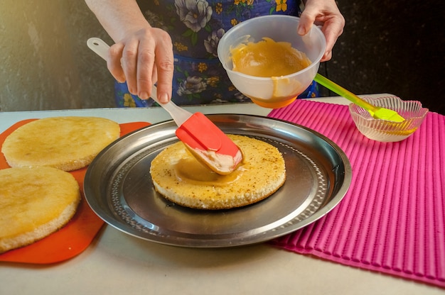 Ingredientes para hornear y utensilios para cocinar bizcocho. Proceso de cocción de bizcocho. Mujer pone la crema en los pasteles