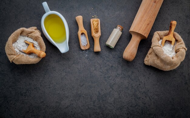 Los ingredientes para la masa de pizza casera en el fondo de piedra oscura.