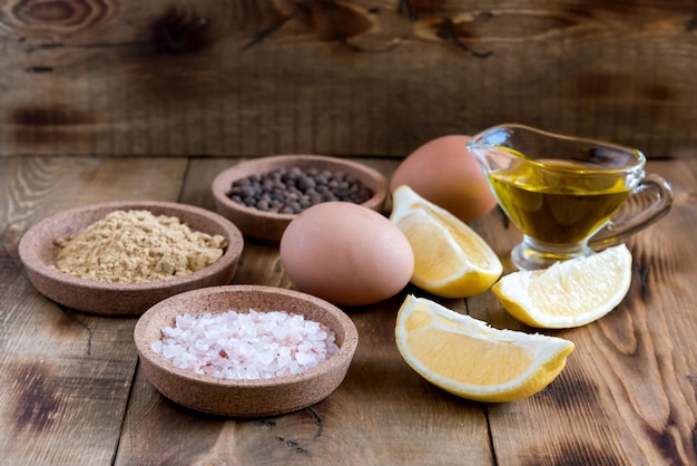 Ingredientes de mayonesa sobre fondo de madera Sal Pimienta Huevos Aceite de limón Ingredientes rústicos para salsa