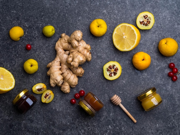 Ingredientes de medicina alternativa para un té caliente picante en el día de invierno concepto de alimentación saludable miel en frascos de vidrio bayas rojas cydonia limón jengibre