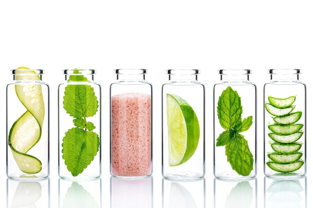 Ingredientes naturales alternativos para el cuidado de la piel en botellas de vidrio aíslan sobre fondo blanco.