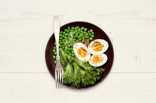 Ingredientes orgánicos para una ensalada con lechuga, guisantes congelados y huevos sobre fondo rústico Concepto de alimentación saludable o nutrición dietética Vista superior