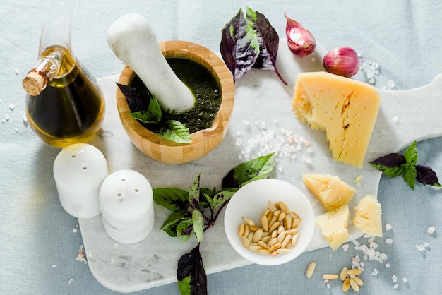 Ingredientes para a preparação de pesto roxo de manjericão italiano com queijo na toalha de mesa azul de linho