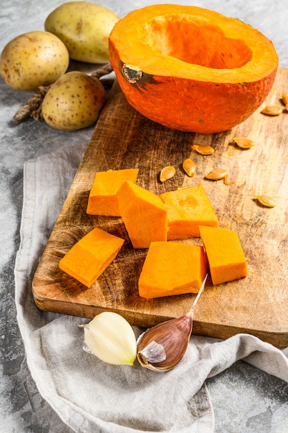 Ingredientes para a sopa de abóbora. Pedaços de abóbora em uma placa de corte. Sopa cremosa.