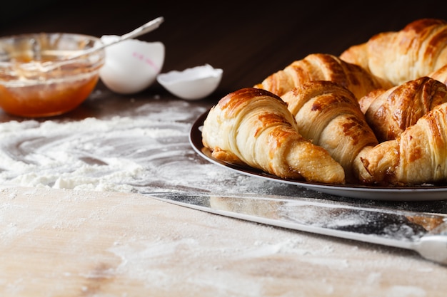 Ingredientes para assar croissants - farinha, colher de pau, rolo, ovos, gemas de ovos