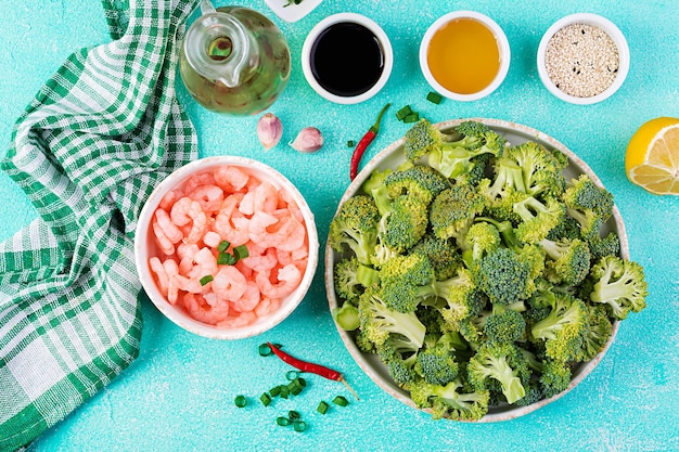 Ingredientes para cozinhar camarão frito com brócolis de perto em uma mesa camarão e brókolis vista superior