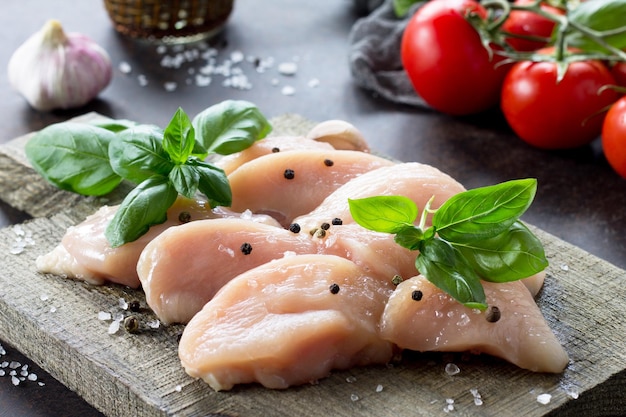 Ingredientes para cozinhar carne de frango fresca em uma tábua e tomates de alho Copiar espaço