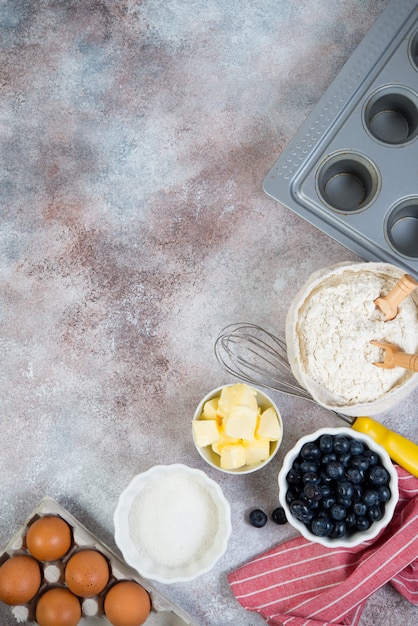 Ingredientes para fazer bolos. Farinha, manteiga, açúcar, frutas, ovos e bolinhos de mentira sobre um fundo de concreto.