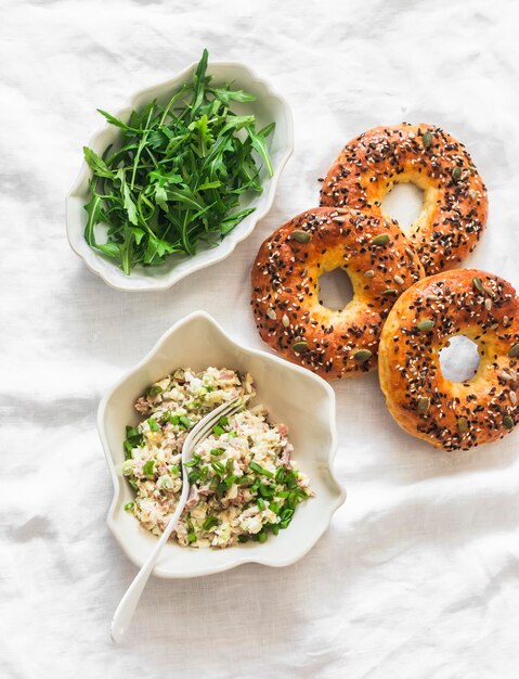 Foto ingredientes para fazer café da manhã brunch lanche atum ovos salada rúcula e bagels em um fundo claro vista superior