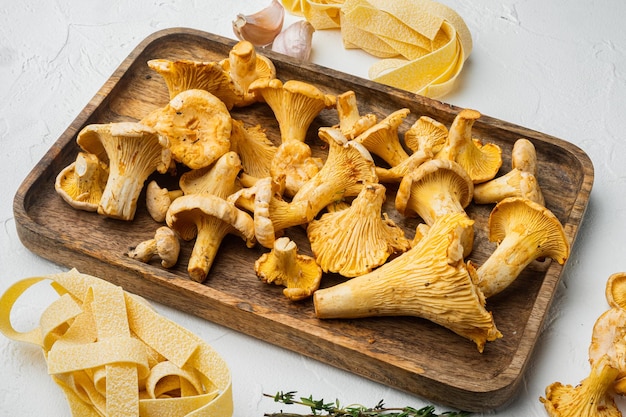 Ingredientes para fazer macarrão italiano com conjunto de chanterelles de cogumelos, no fundo da mesa de pedra branca