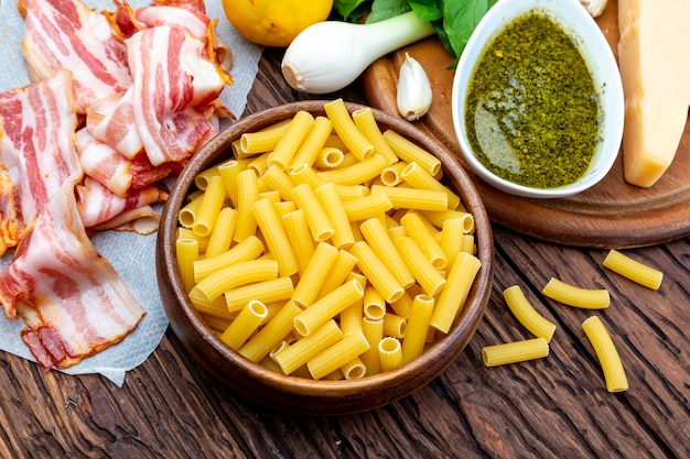 Ingredientes para fazer macarrão pesto caseiro. Com cebola e bacon, queijo, manjericão, pinhões, alho.